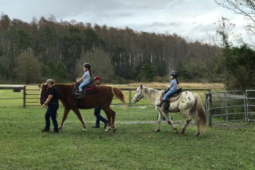 a group of people riding on the back of a horse in a field